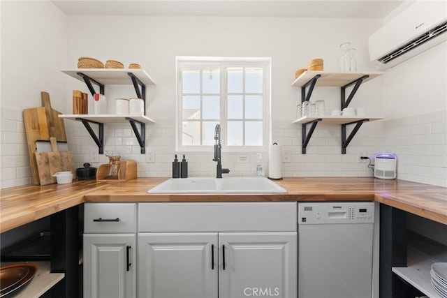 kitchen with butcher block countertops, sink, a wall mounted AC, and white dishwasher