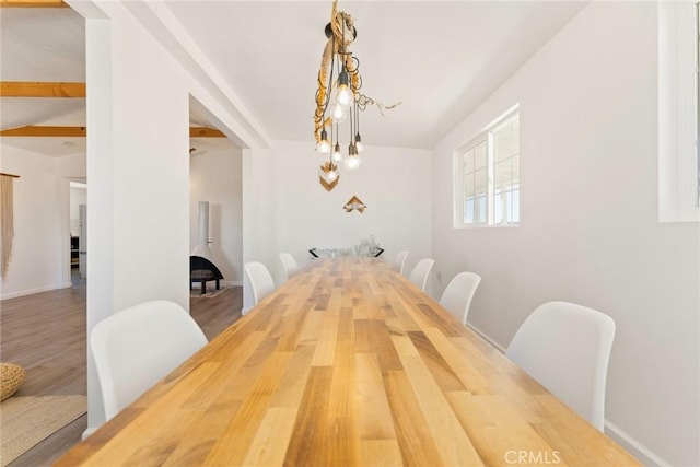 dining room with beamed ceiling, a notable chandelier, and hardwood / wood-style flooring