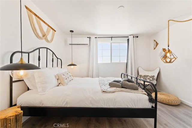 bedroom featuring hardwood / wood-style flooring and a wall unit AC