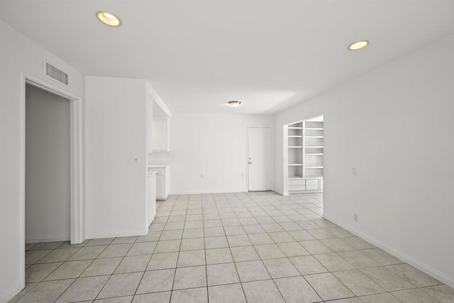 spare room featuring built in shelves and light tile patterned flooring