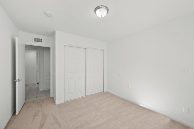 unfurnished bedroom with light colored carpet and a closet