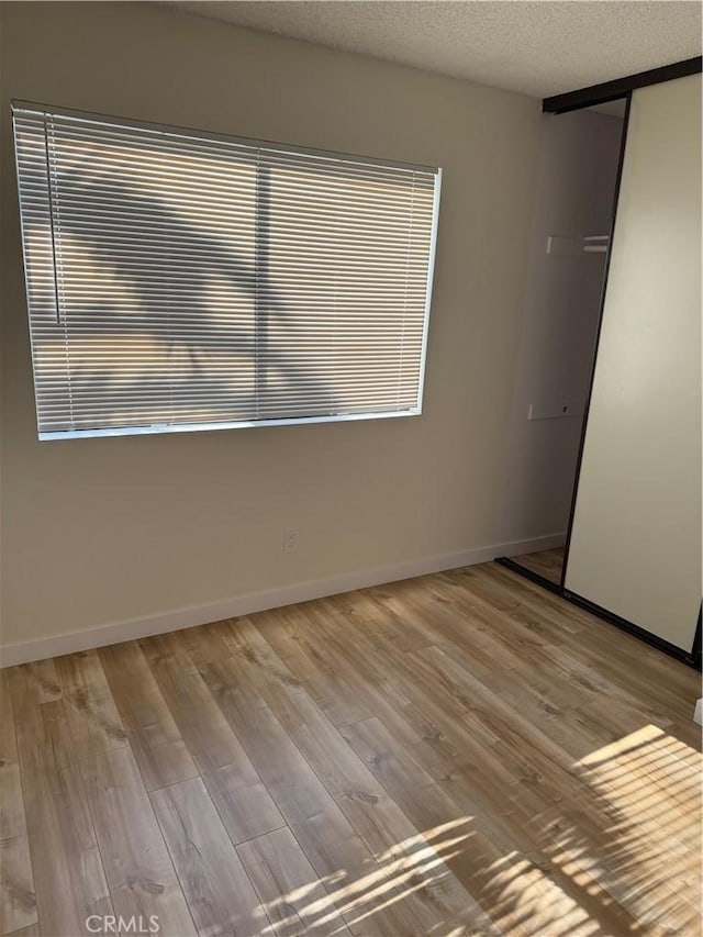 unfurnished room featuring a textured ceiling and light hardwood / wood-style floors