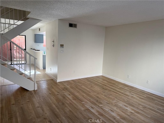 empty room with hardwood / wood-style flooring and a textured ceiling