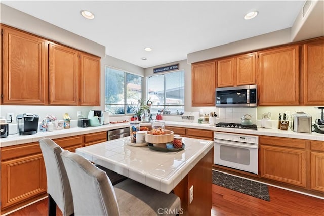 kitchen featuring a kitchen bar, appliances with stainless steel finishes, dark hardwood / wood-style floors, a kitchen island, and tile counters