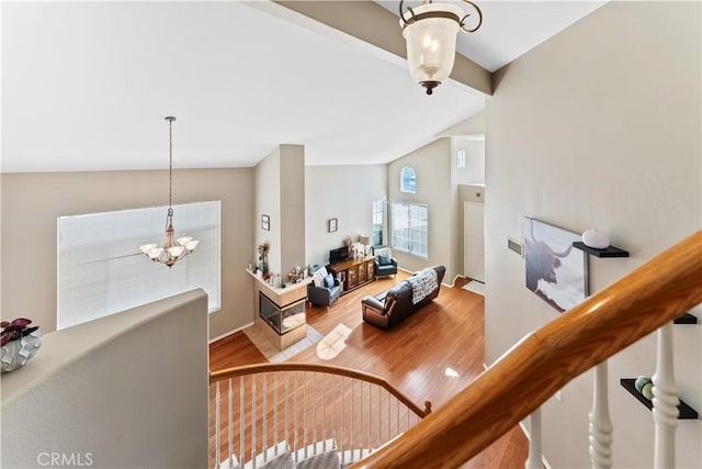 staircase with a chandelier, hardwood / wood-style flooring, and lofted ceiling