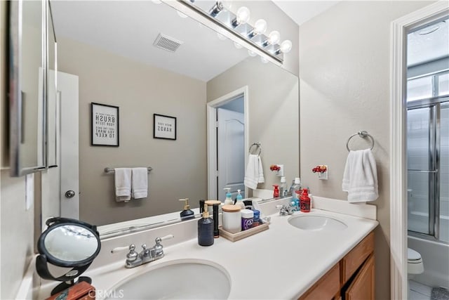 full bathroom featuring shower / bath combination with glass door, vanity, and toilet