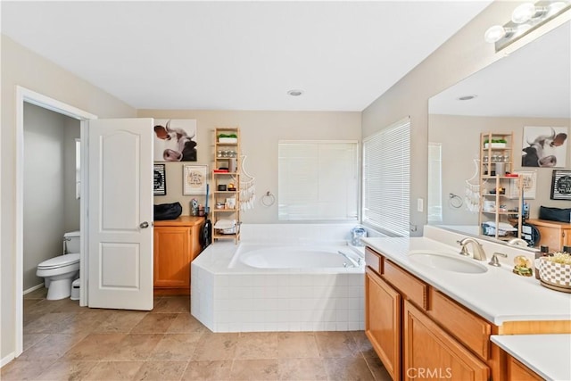 bathroom with tiled bath, vanity, and toilet