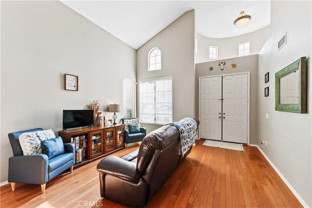 living room with a towering ceiling and wood-type flooring