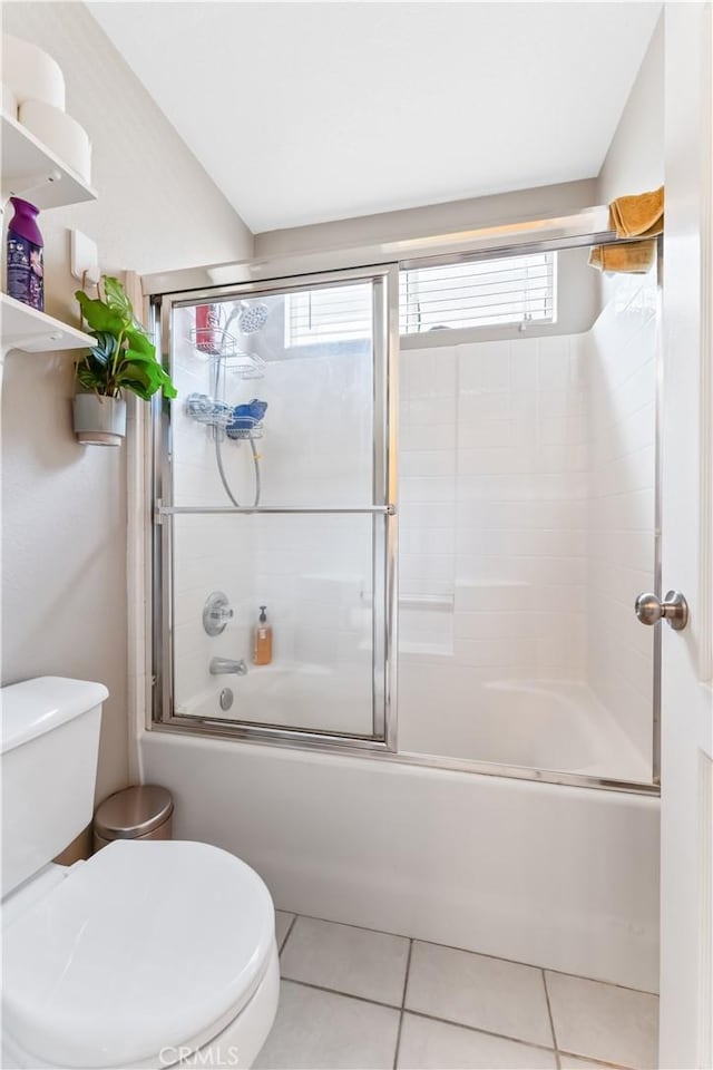 bathroom featuring tile patterned flooring, toilet, and enclosed tub / shower combo