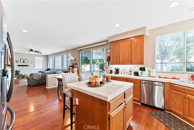 kitchen featuring appliances with stainless steel finishes, a center island, a wealth of natural light, and dark wood-type flooring