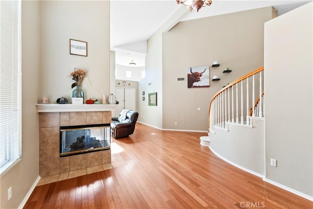 foyer entrance featuring a notable chandelier, wood-type flooring, a fireplace, and high vaulted ceiling