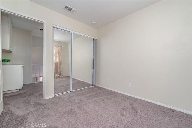 unfurnished bedroom featuring light carpet and a closet