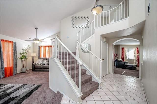 stairs with ceiling fan, a towering ceiling, and carpet