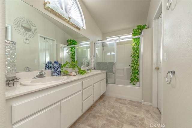 bathroom featuring vanity, bath / shower combo with glass door, and vaulted ceiling