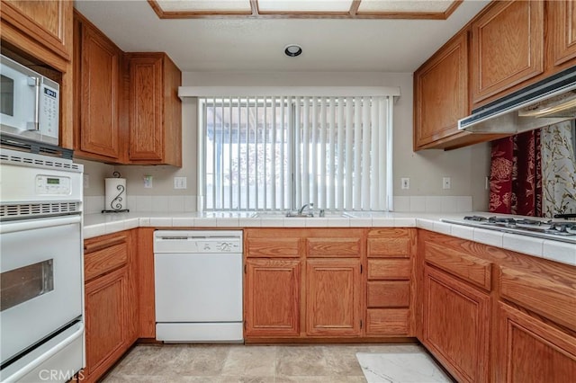 kitchen featuring tile counters, white appliances, sink, and extractor fan