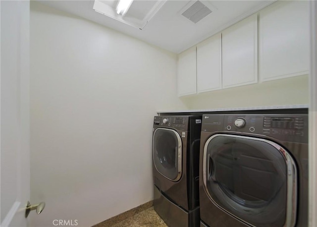 clothes washing area with washer and dryer and cabinets