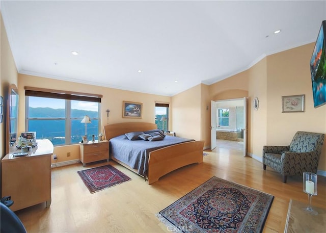 bedroom with multiple windows, a water view, ornamental molding, and light wood-type flooring