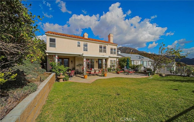 back of property featuring a mountain view, a yard, and a patio