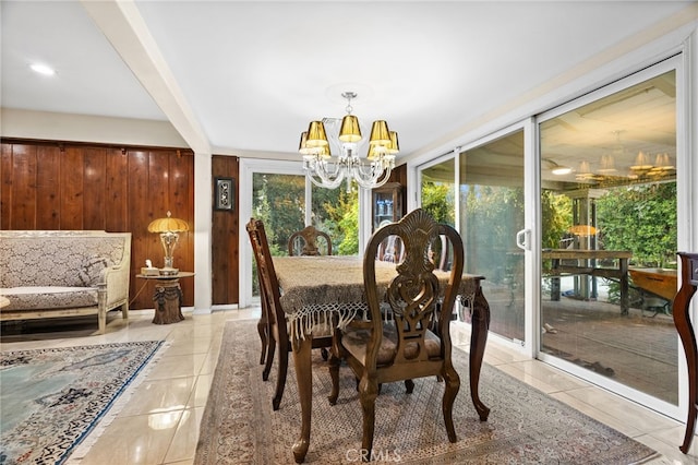 dining space with wooden walls, plenty of natural light, and a notable chandelier