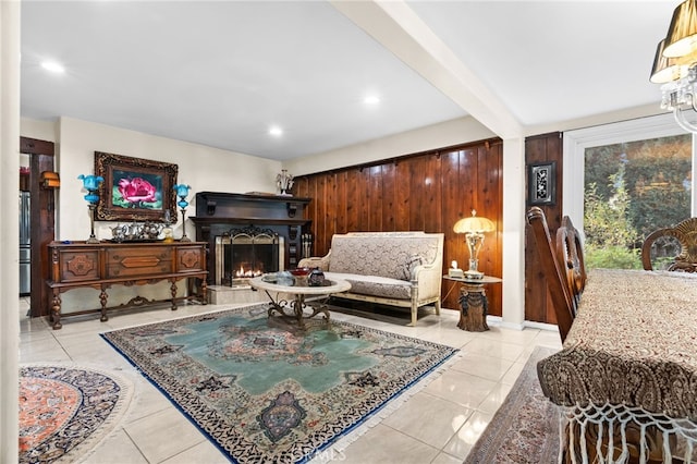 living room with light tile patterned floors, beam ceiling, and wood walls