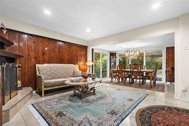 living room featuring a notable chandelier, light tile patterned floors, and wooden walls