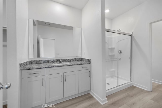 bathroom featuring vanity, an enclosed shower, and wood-type flooring