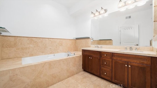 bathroom featuring tile patterned flooring, vanity, and tiled bath