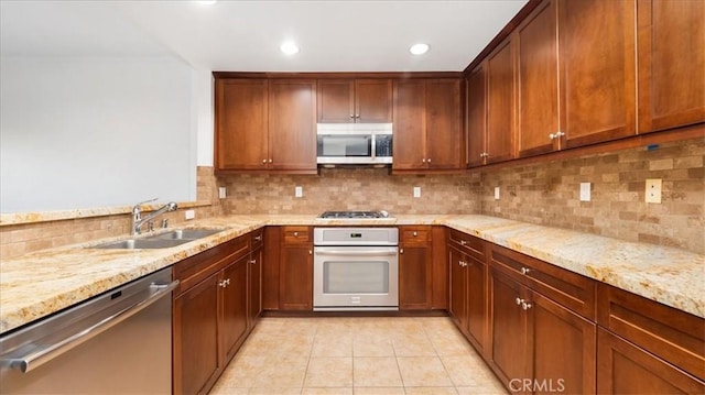 kitchen with light tile patterned flooring, light stone countertops, sink, and appliances with stainless steel finishes