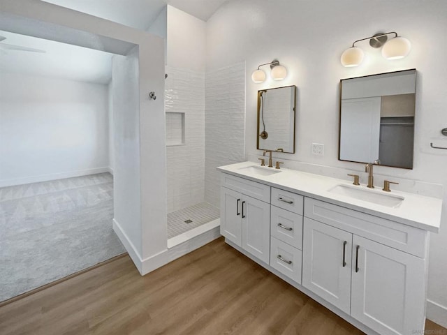 bathroom with ceiling fan, tiled shower, hardwood / wood-style floors, and vanity