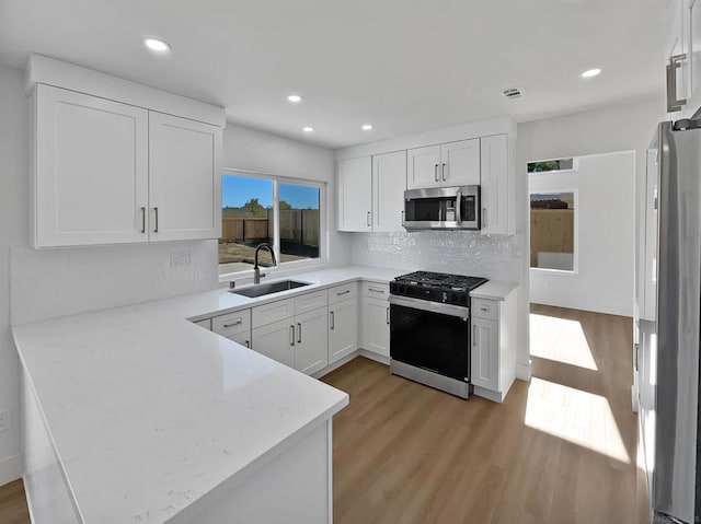 kitchen with stainless steel appliances, white cabinets, sink, and kitchen peninsula