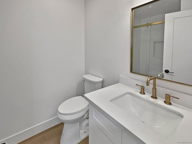 bathroom with wood-type flooring, walk in shower, vanity, and toilet