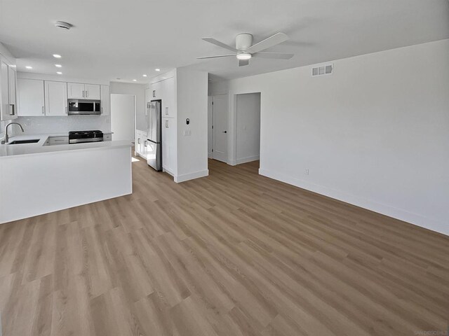 kitchen featuring appliances with stainless steel finishes, light hardwood / wood-style flooring, white cabinetry, and sink