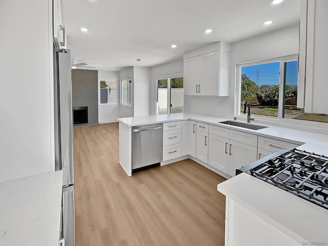 kitchen featuring white cabinets, stainless steel appliances, a tile fireplace, and kitchen peninsula