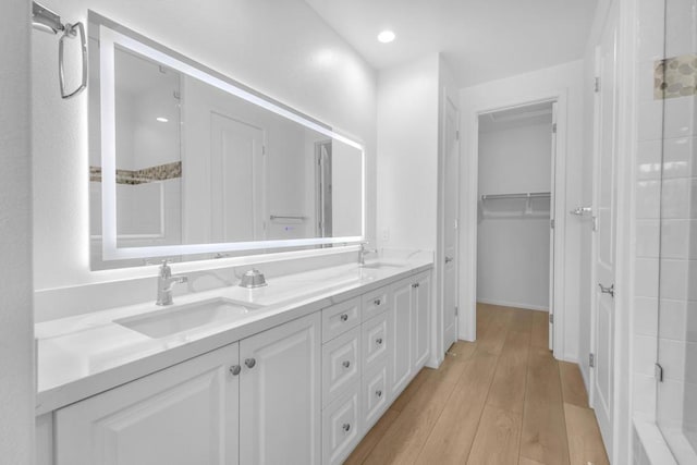 bathroom with a tile shower, hardwood / wood-style floors, and vanity