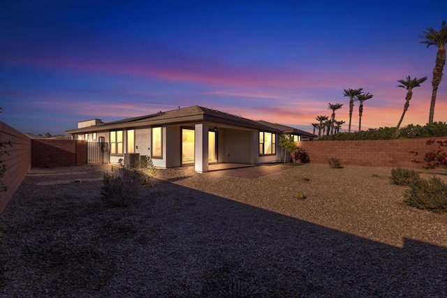 back house at dusk featuring cooling unit