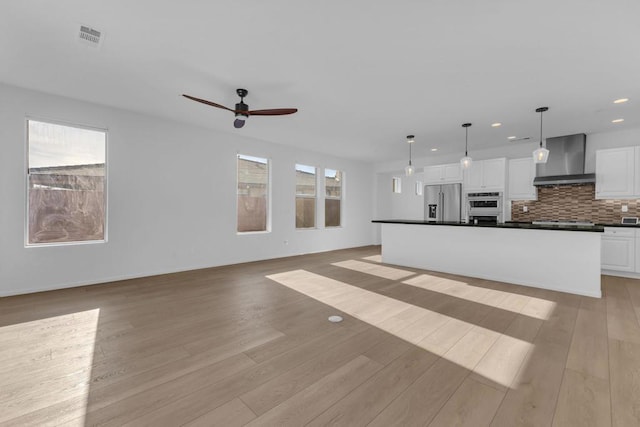 unfurnished living room featuring light wood-type flooring and ceiling fan