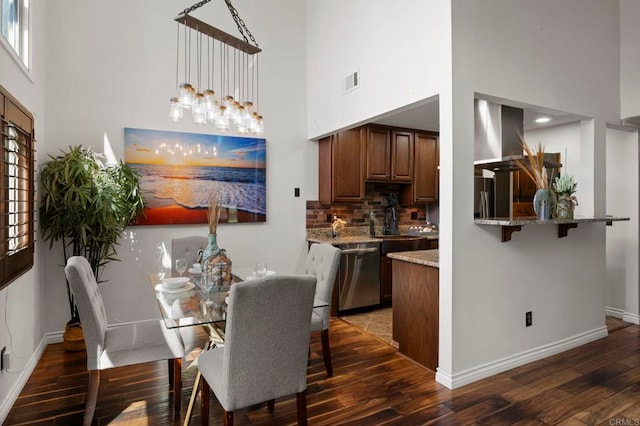 dining space featuring sink, a towering ceiling, and dark wood-type flooring