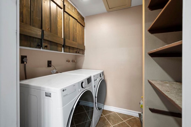 clothes washing area featuring separate washer and dryer, dark tile patterned floors, and cabinets