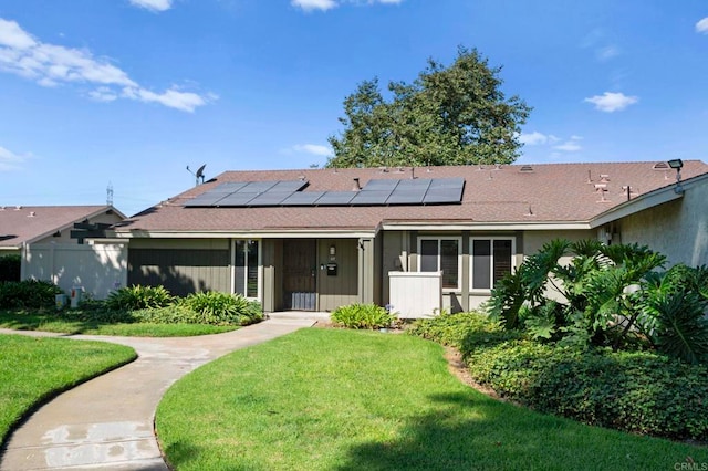 view of front of home featuring a front yard and solar panels