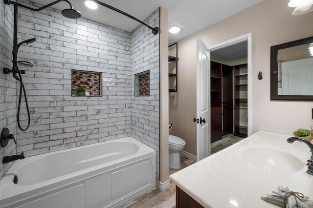 full bathroom featuring hardwood / wood-style floors, vanity, tiled shower / bath combo, and toilet