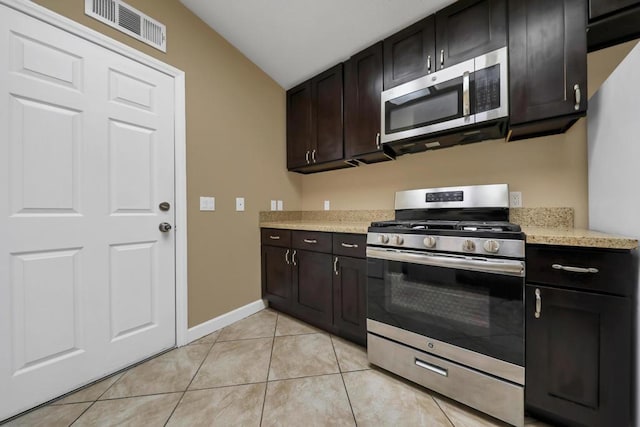 kitchen with light tile patterned floors, appliances with stainless steel finishes, dark brown cabinets, and lofted ceiling