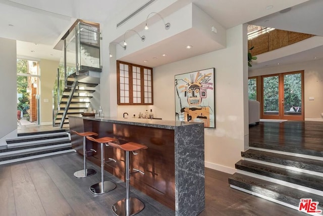 bar featuring stone counters and dark hardwood / wood-style flooring