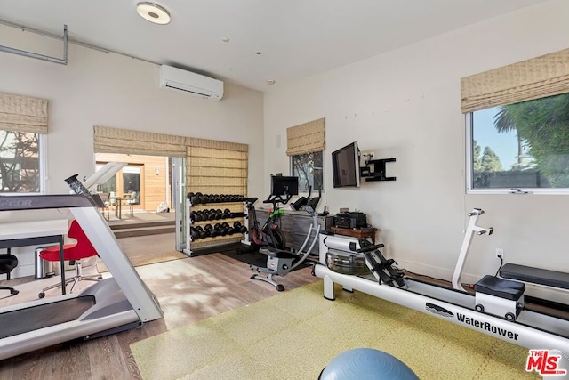 exercise room with wood-type flooring and an AC wall unit