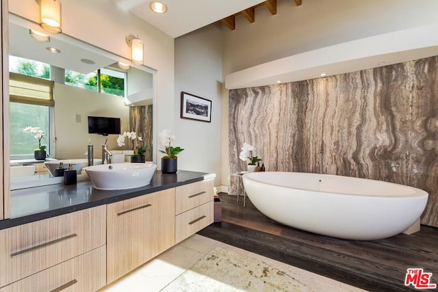 bathroom with hardwood / wood-style floors, vanity, and a tub