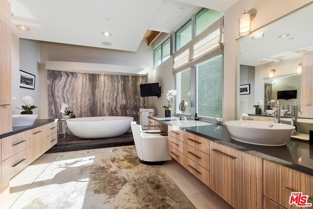 bathroom featuring tile patterned flooring, vanity, and a tub to relax in