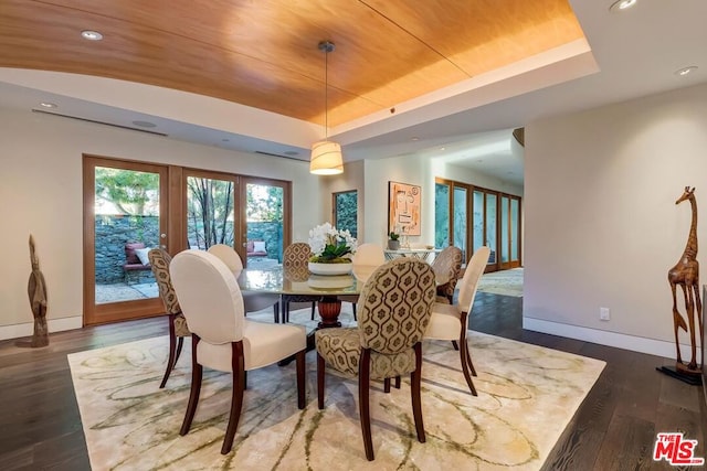 dining area with a raised ceiling, dark wood-type flooring, and french doors