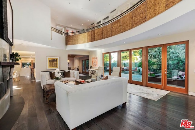 living room featuring a large fireplace, french doors, dark hardwood / wood-style floors, and a high ceiling