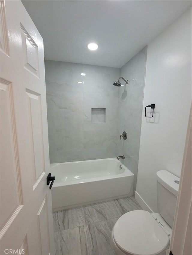 bathroom featuring tiled shower / bath combo and toilet