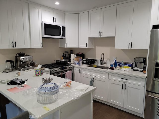 kitchen with light stone countertops, white cabinetry, sink, stainless steel appliances, and dark hardwood / wood-style floors