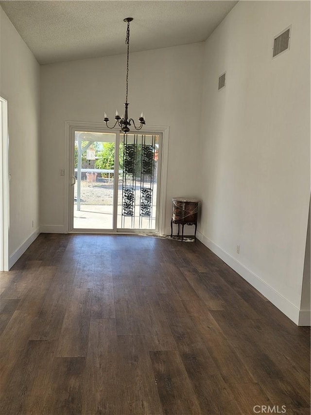 unfurnished dining area with a textured ceiling, dark hardwood / wood-style floors, high vaulted ceiling, and a notable chandelier